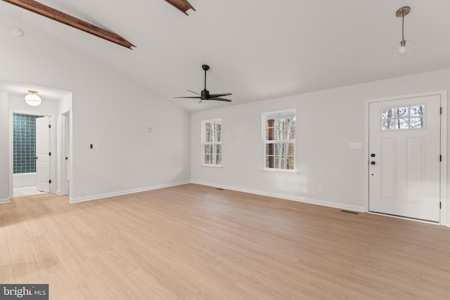 unfurnished living room with lofted ceiling with beams, a healthy amount of sunlight, light wood-type flooring, and ceiling fan