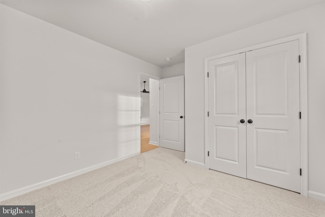 unfurnished bedroom featuring light colored carpet and a closet