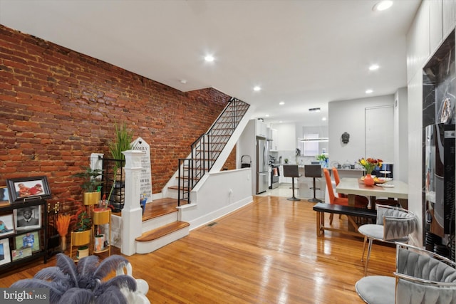 living room featuring light hardwood / wood-style floors and brick wall