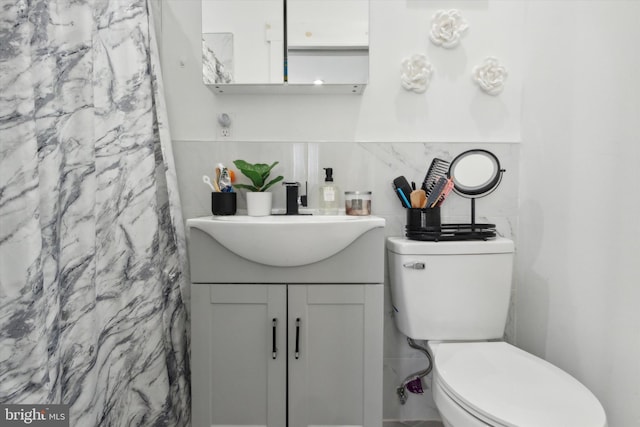 bathroom featuring toilet, vanity, tile walls, and a shower with shower curtain