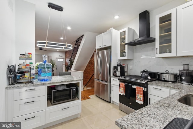 kitchen featuring pendant lighting, appliances with stainless steel finishes, wall chimney exhaust hood, and white cabinets