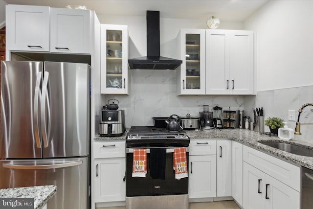 kitchen with sink, appliances with stainless steel finishes, light stone countertops, wall chimney exhaust hood, and white cabinets