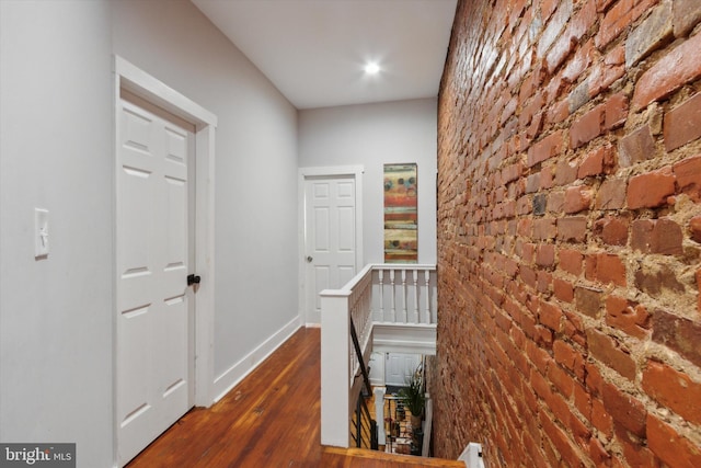 corridor featuring dark wood-type flooring and brick wall