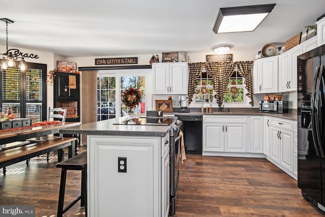 kitchen featuring white cabinets, black appliances, dark wood-type flooring, and a center island