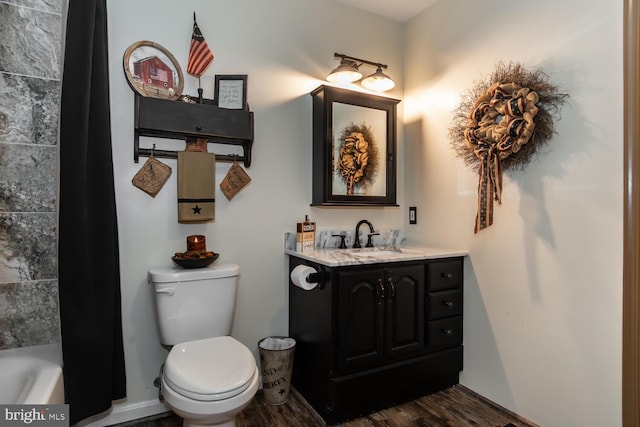 bathroom with toilet, vanity, hardwood / wood-style floors, and a tub