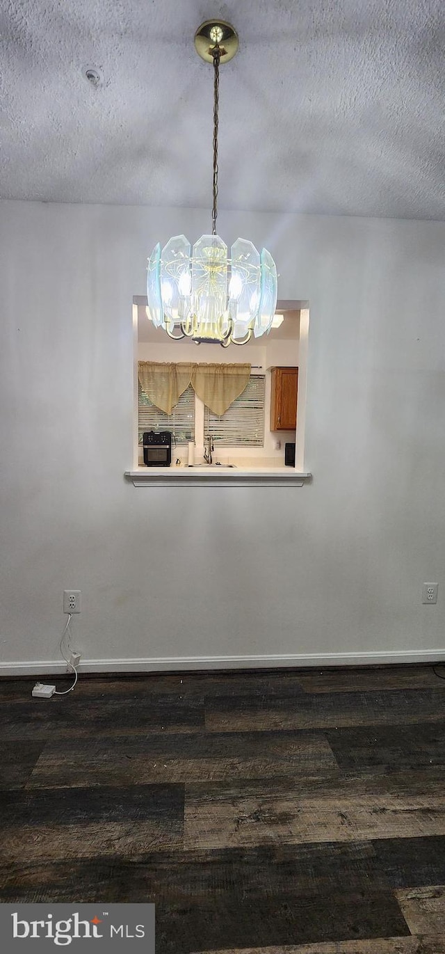 unfurnished dining area featuring dark hardwood / wood-style flooring and a textured ceiling