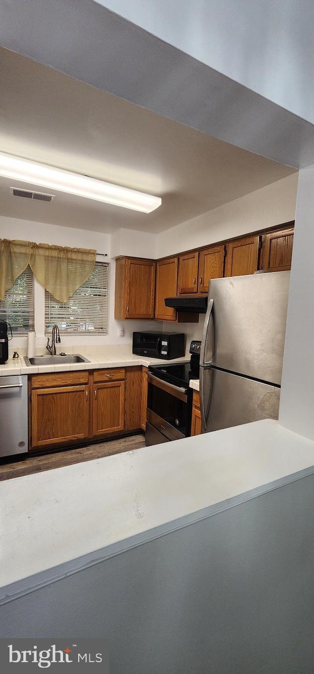 kitchen with stainless steel appliances, extractor fan, and sink