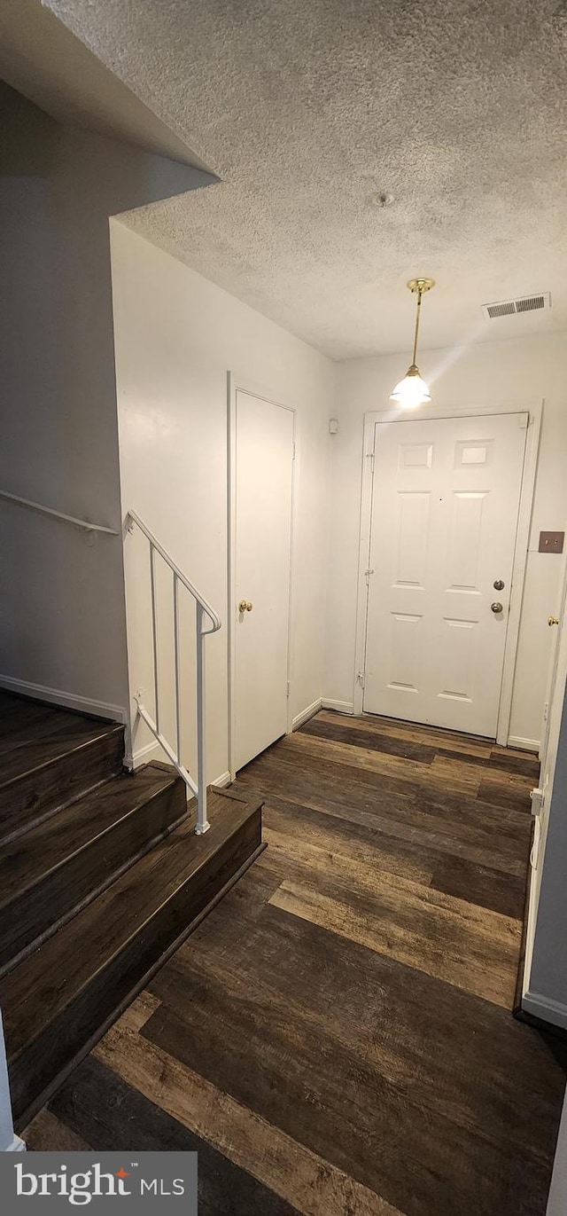 foyer with a textured ceiling and dark wood-type flooring