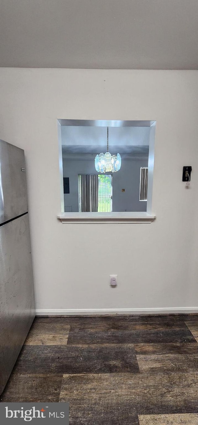 empty room with hardwood / wood-style flooring and a chandelier