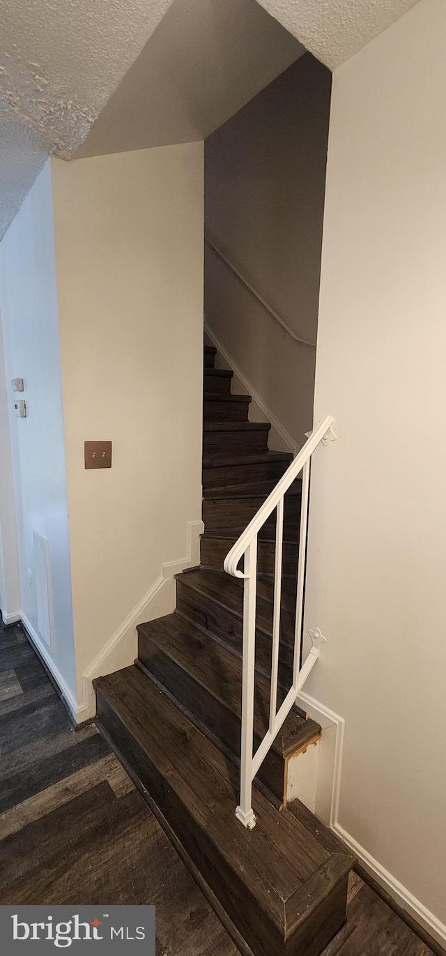 staircase with hardwood / wood-style floors and a textured ceiling