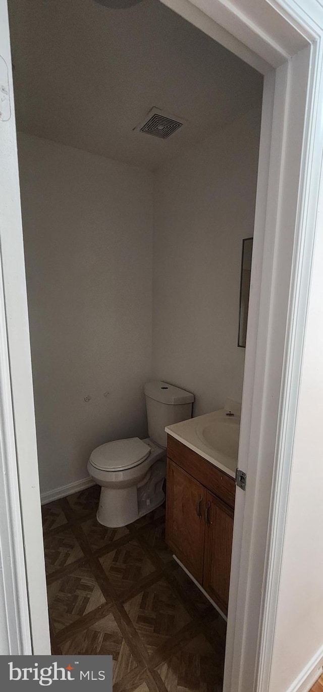 bathroom featuring parquet flooring, vanity, and toilet