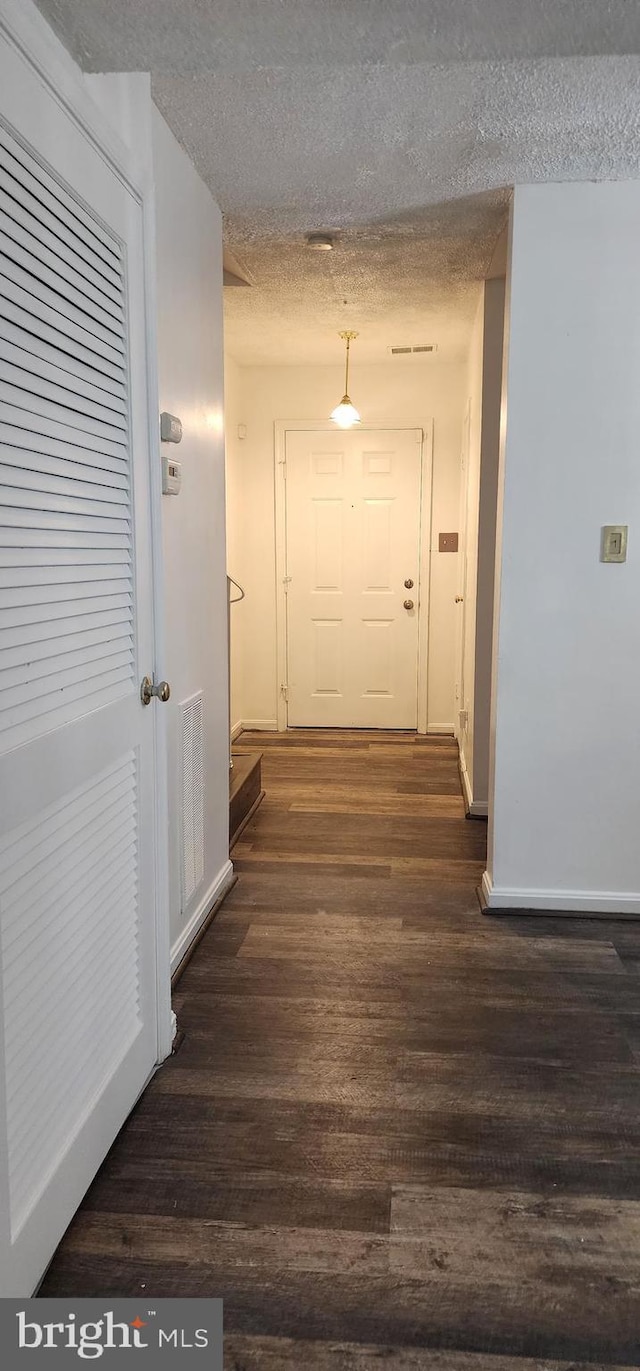 hall with dark hardwood / wood-style flooring and a textured ceiling