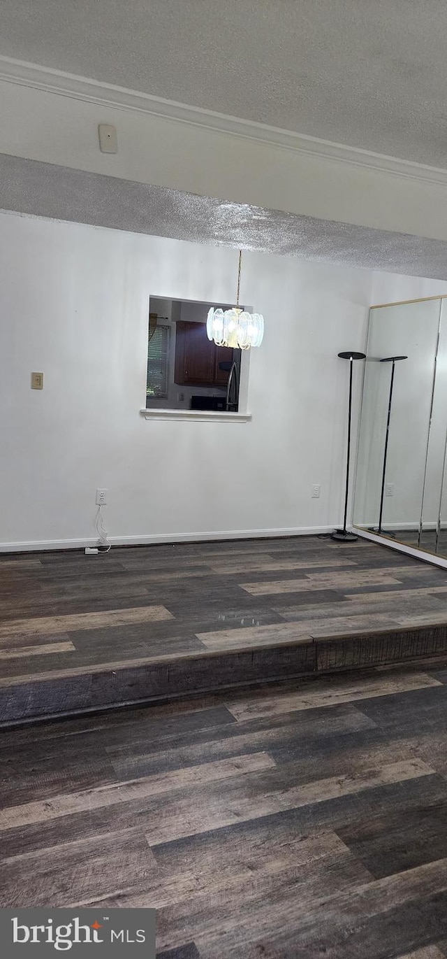 empty room featuring wood-type flooring, a textured ceiling, and ornamental molding