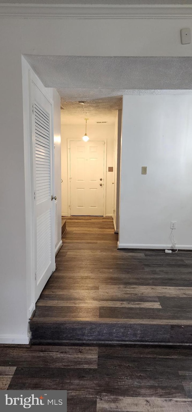 hall with dark hardwood / wood-style flooring and a textured ceiling