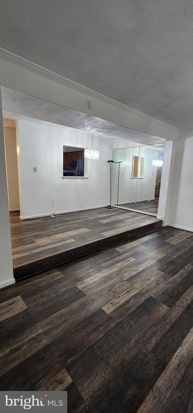 basement featuring crown molding, dark hardwood / wood-style flooring, and a textured ceiling