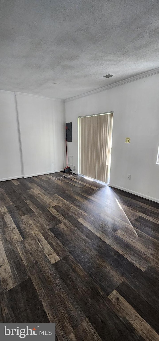 empty room featuring dark hardwood / wood-style flooring, a textured ceiling, and electric panel