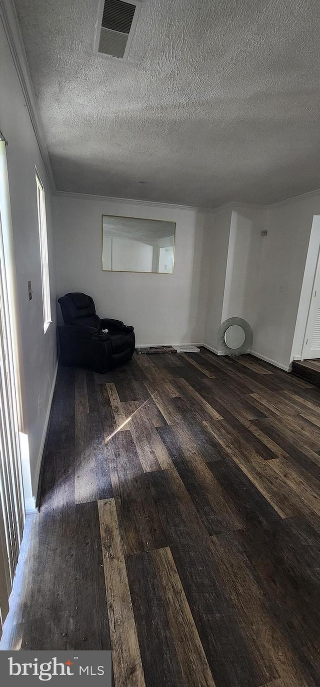 unfurnished living room featuring dark wood-type flooring and a textured ceiling