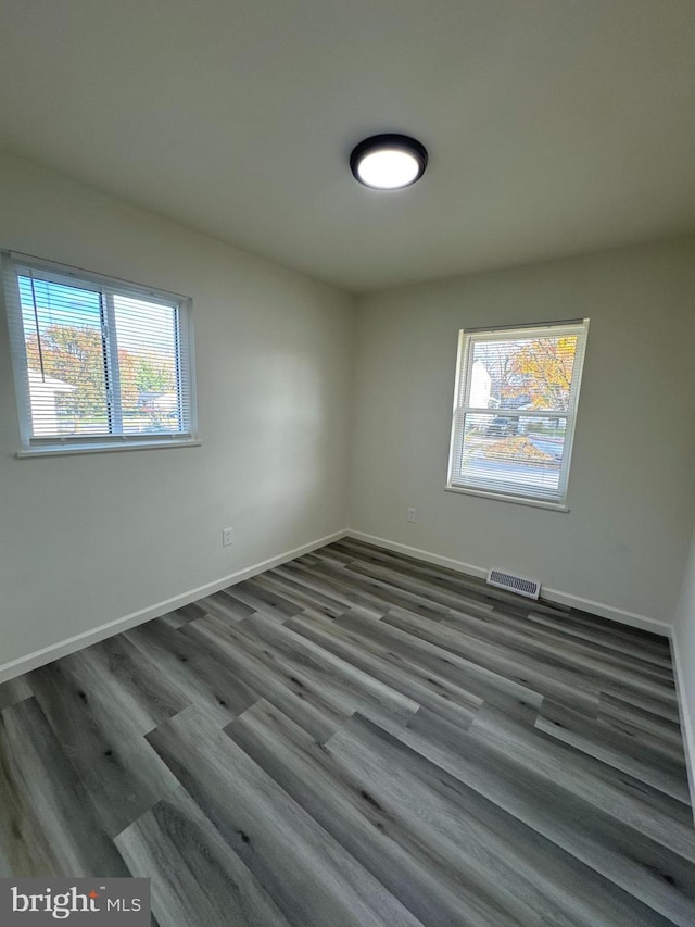 empty room with plenty of natural light and dark hardwood / wood-style flooring