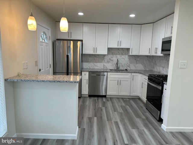 kitchen with kitchen peninsula, appliances with stainless steel finishes, sink, and white cabinets