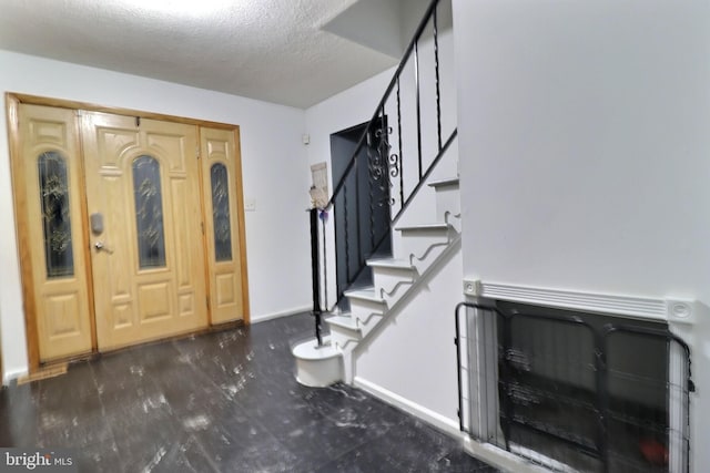 entrance foyer with stairway, a textured ceiling, and baseboards