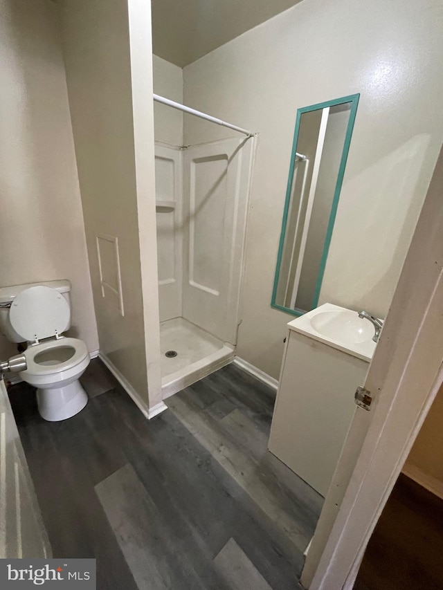 bathroom featuring a shower, hardwood / wood-style floors, vanity, and toilet