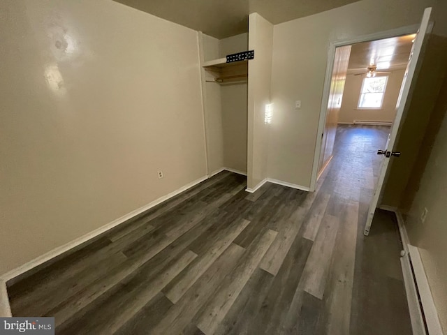 unfurnished bedroom with dark hardwood / wood-style flooring, a baseboard radiator, and a closet