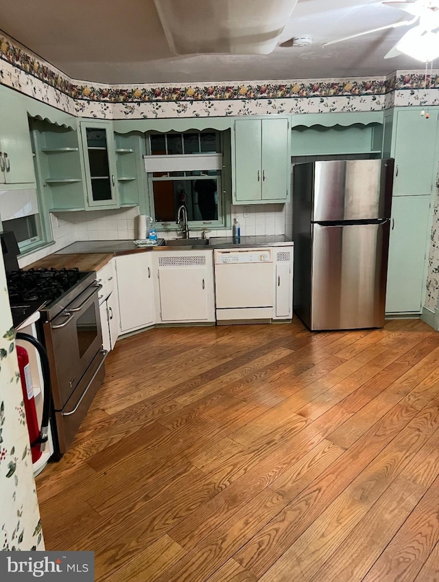 kitchen featuring stainless steel appliances, open shelves, wood finished floors, and tasteful backsplash