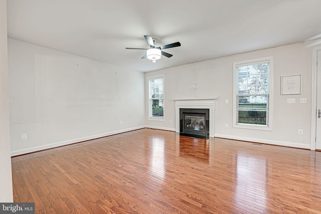 unfurnished living room with ceiling fan, light wood-type flooring, and a wealth of natural light