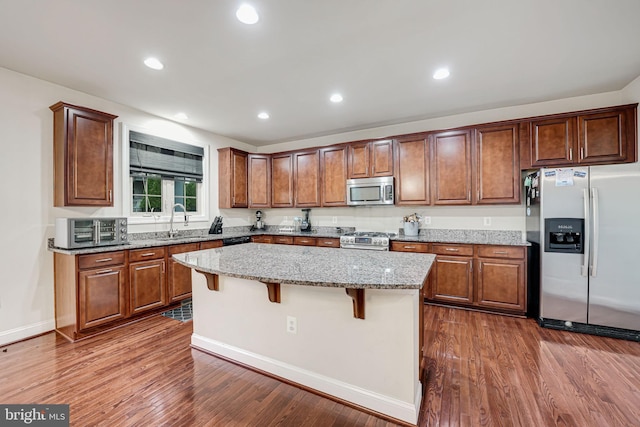 kitchen with a kitchen island, dark hardwood / wood-style flooring, a breakfast bar area, and appliances with stainless steel finishes