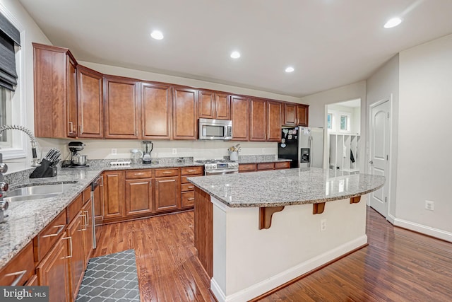 kitchen featuring appliances with stainless steel finishes, dark hardwood / wood-style floors, a kitchen island, and sink