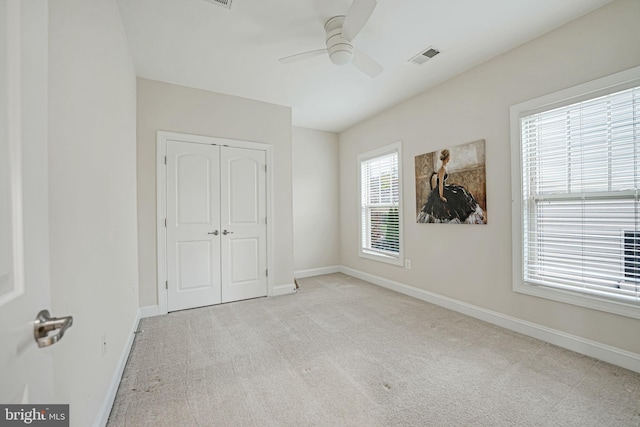 unfurnished bedroom with light carpet, a closet, and ceiling fan