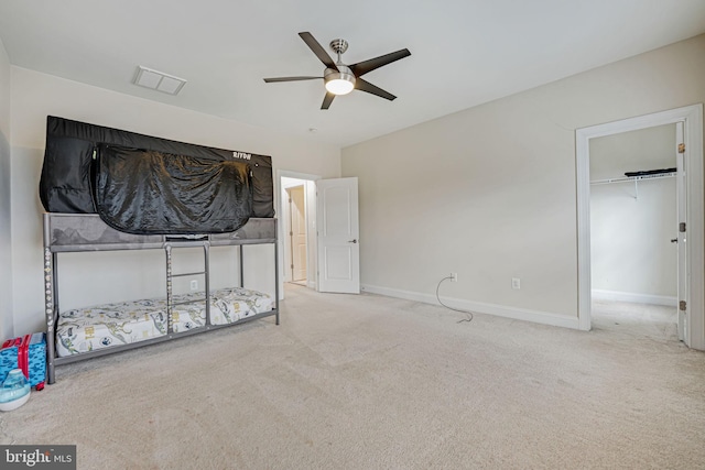 unfurnished bedroom featuring ceiling fan, a closet, light carpet, and a spacious closet