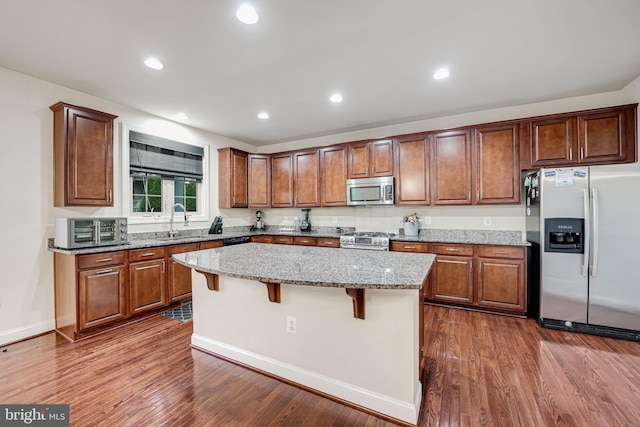 2216 Turnbuckle Ln, Woodbridge, VA 22191 - kitchen with appliances with stainless steel finishes, a sink, a kitchen island, light stone counters, and dark wood-style floors
