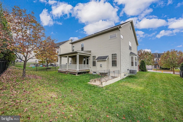 rear view of property featuring central air condition unit, a wooden deck, and a lawn