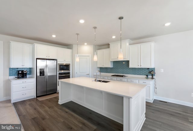 kitchen with a center island with sink, white cabinetry, appliances with stainless steel finishes, dark hardwood / wood-style flooring, and hanging light fixtures