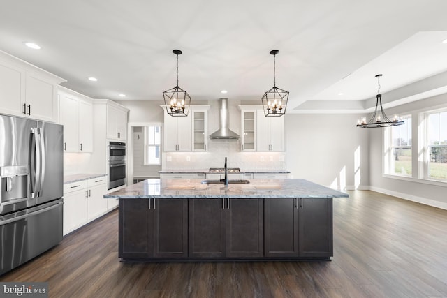 kitchen featuring white cabinets, wall chimney exhaust hood, light stone counters, and appliances with stainless steel finishes