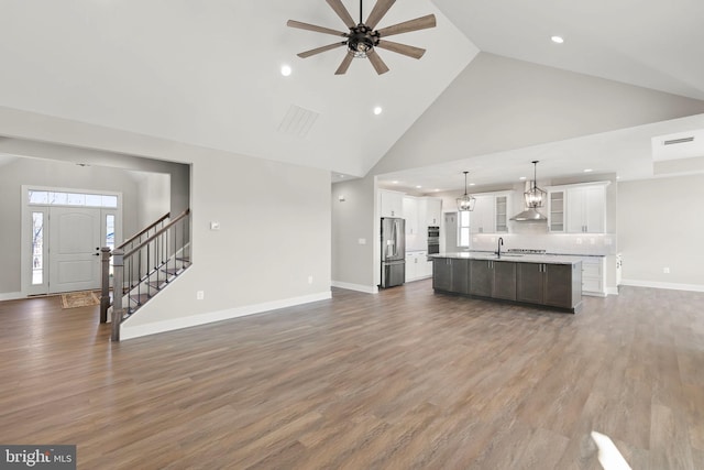 unfurnished living room featuring ceiling fan, high vaulted ceiling, and dark wood-type flooring