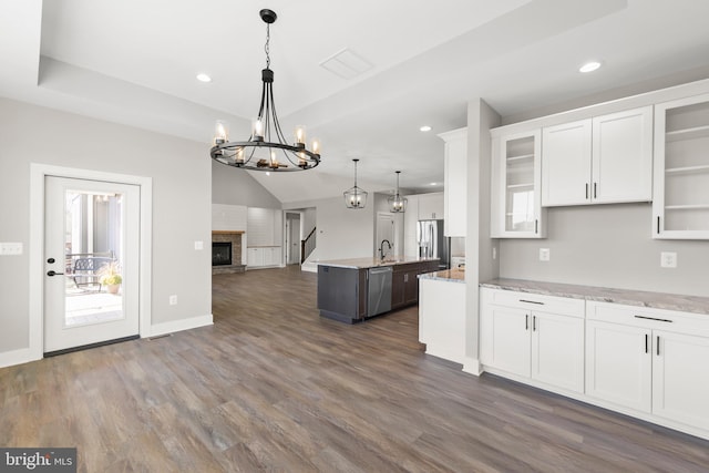 kitchen with a kitchen island with sink, hanging light fixtures, white cabinets, and stainless steel appliances