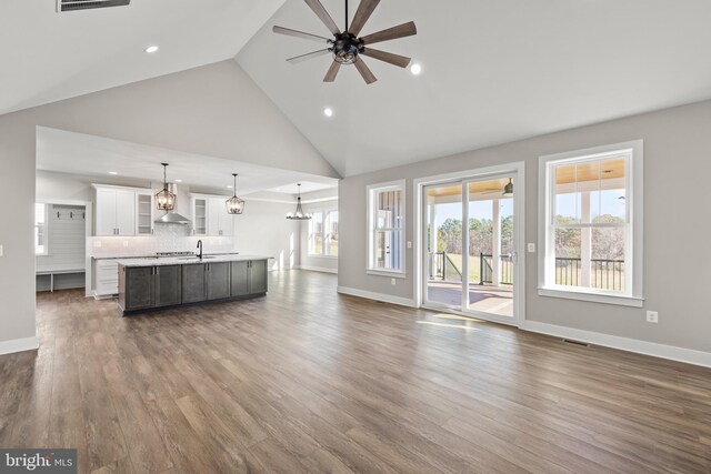 unfurnished living room featuring high vaulted ceiling, ceiling fan, dark wood-type flooring, and sink