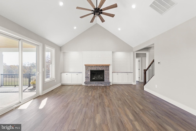 unfurnished living room with a stone fireplace, ceiling fan, dark wood-type flooring, and vaulted ceiling