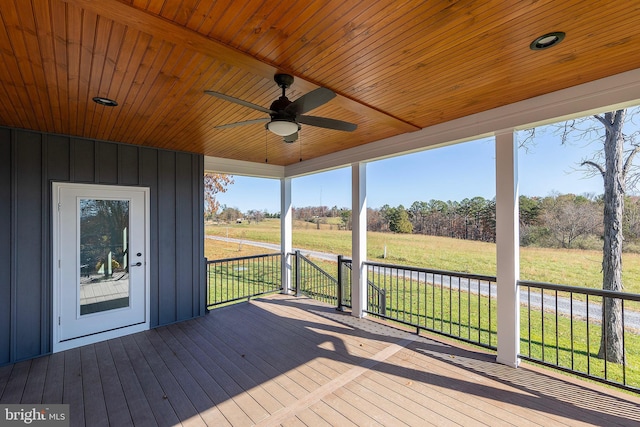 wooden deck featuring a lawn, ceiling fan, and a rural view