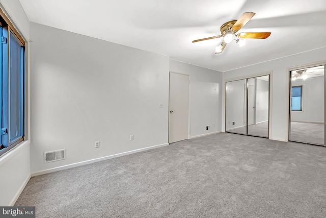 unfurnished bedroom with ceiling fan, two closets, and carpet floors