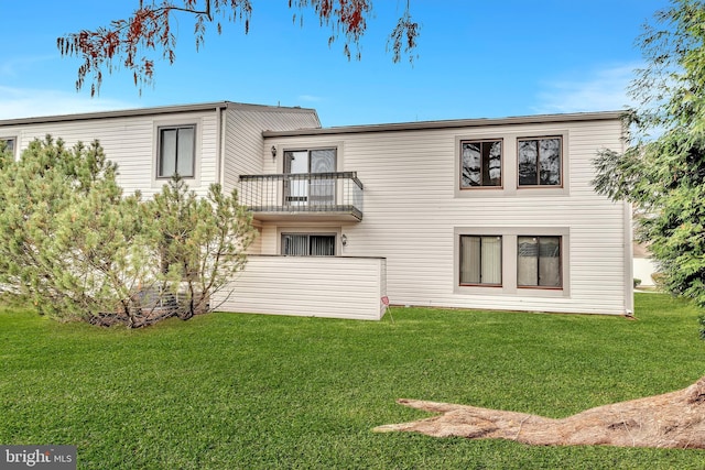 back of property featuring a balcony and a yard