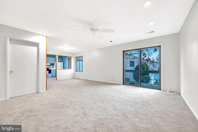 empty room with plenty of natural light, ceiling fan, and light colored carpet