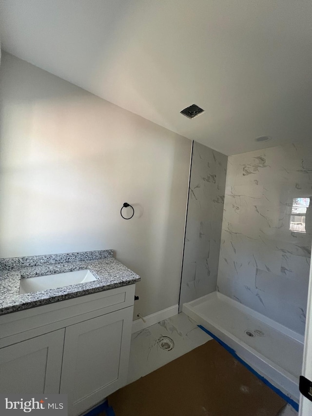 bathroom with vanity and a tile shower