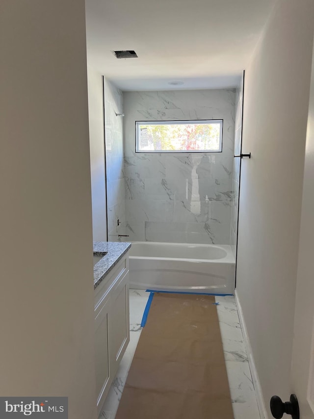 bathroom with tiled shower / bath combo and vanity