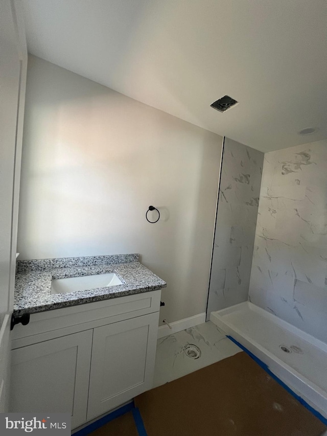 bathroom with vanity and tiled shower