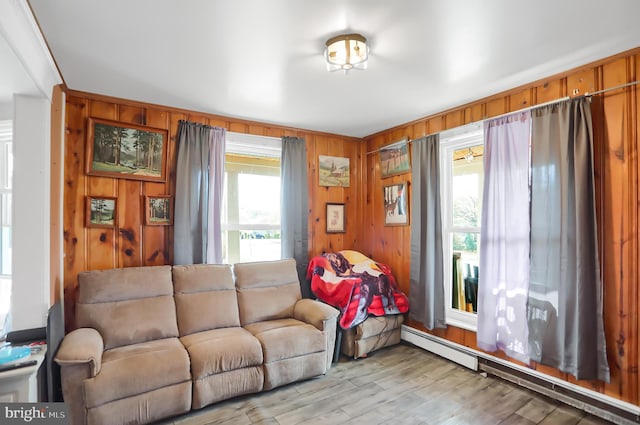 living room featuring wood walls, a baseboard heating unit, a wealth of natural light, and light hardwood / wood-style flooring