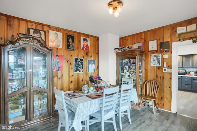 dining area featuring wood walls and dark hardwood / wood-style flooring