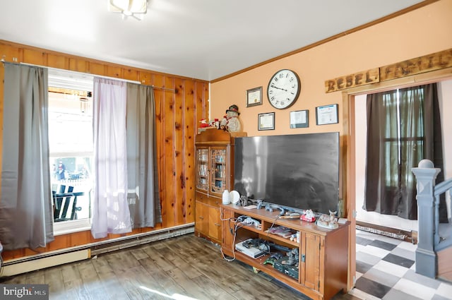 living room with a baseboard heating unit, hardwood / wood-style floors, wood walls, and ornamental molding